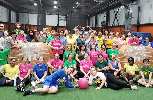 Team of over 30 people pose for the camera after playing bumper ball