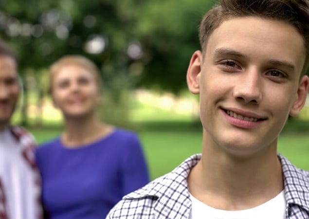 Boy standing forefront with parents behind him