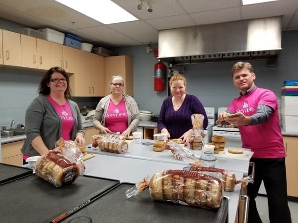 Four Skyline employees preparing 4 dozen bagels with cream cheese