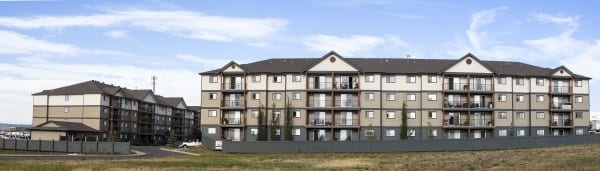 Two, four storey apartment buildings with a clear blue sky