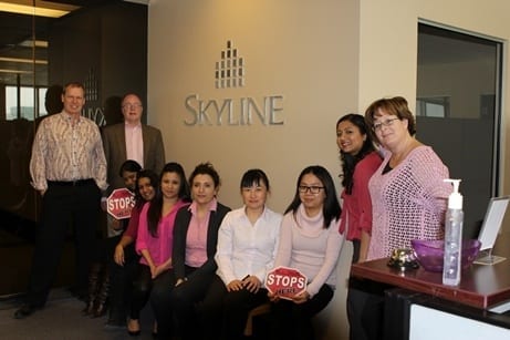 Office staff wearing pink shirts and holding stop signs