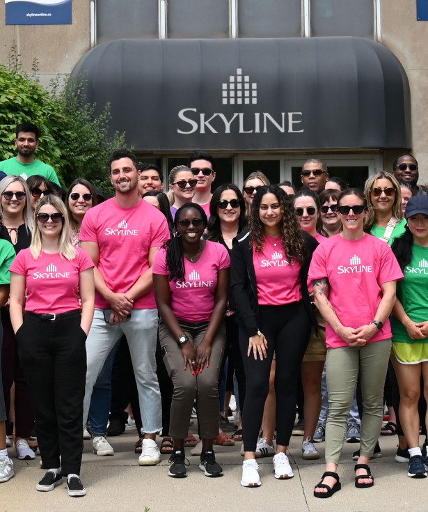 Skyline's smiling while standing outside of a Skyline building