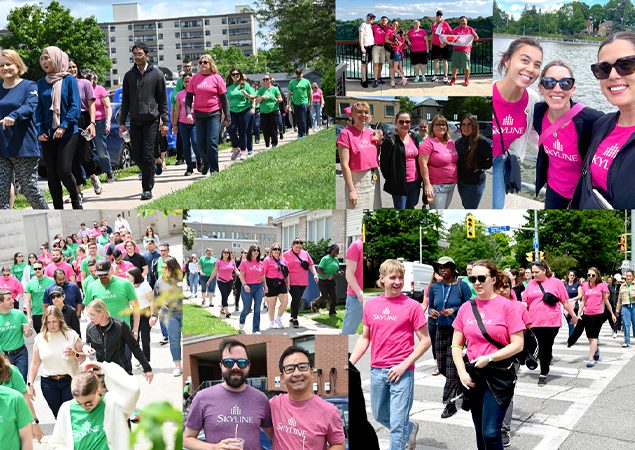 Groups of people in bright Skyline t-shirts walk down the street on a sunny day.